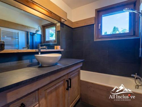 La salle de bains est pourvue d'un lavabo, d'une baignoire et d'une fenêtre. dans l'établissement Joli appartement avec balcon, à Megève