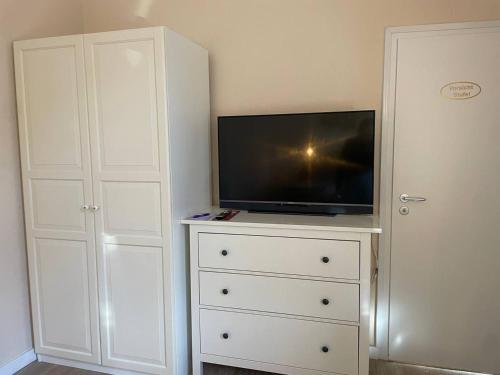 a white dresser with a television on top of it at Hotel Deichvoigt in Cuxhaven