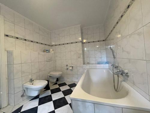 a bathroom with a toilet and a tub and a sink at Hotel Deichvoigt in Cuxhaven