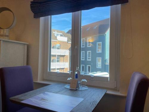 a table with a bottle of wine next to a window at Hotel Deichvoigt in Cuxhaven