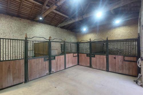 a horse stable with wooden gates in a building at Studio du domaine équestre B & G in Saint-Médard