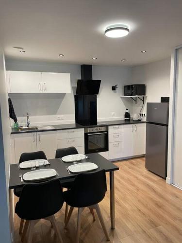 La cuisine est équipée d'une table et de chaises noires ainsi que d'un réfrigérateur. dans l'établissement Logement cœur de Nancy, à Nancy