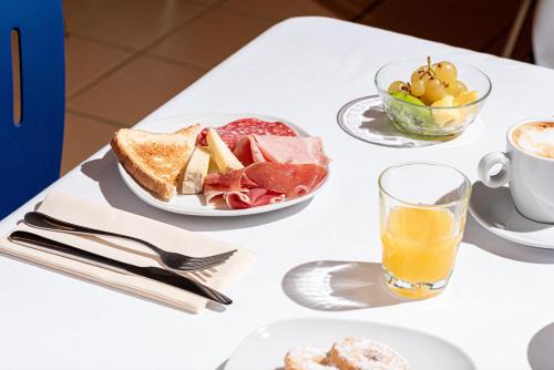 a table with a plate of food and a cup of orange juice at Phi Hotel Homy Druento in Druento