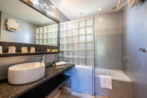 une salle de bain avec une baignoire, un lavabo et un miroir dans l'établissement Résidence Domaine De Caranella, à Porto-Vecchio