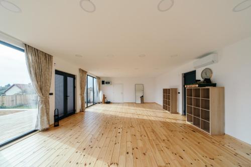 an empty room with a wooden floor and large windows at SunMoon Kosmaj kućice i prostor za događaje in Sopot