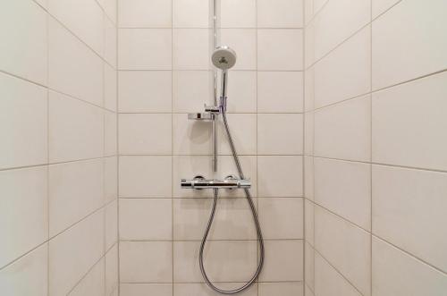 HinteにあるHaus Schlossgartenの白いタイル張りのバスルーム(シャワーヘッド付)