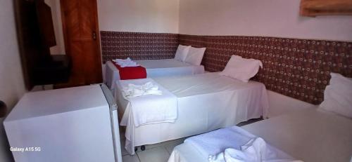 a hotel room with two beds and two tables at Recanto Pequena Sereia in São Mateus