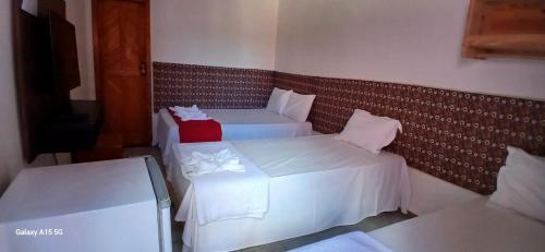 a room with two beds with white sheets and pink pillows at Recanto Pequena Sereia in São Mateus