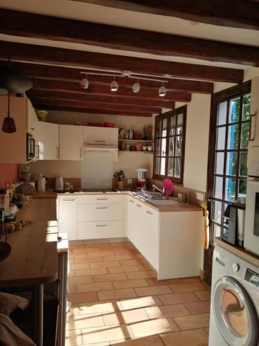 une cuisine avec des armoires blanches et une machine à laver dans l'établissement Maison de ville avec jardin, à Saujon