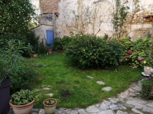un jardin avec des fleurs et des plantes devant un bâtiment dans l'établissement Maison de ville avec jardin, à Saujon