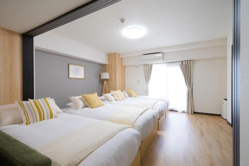 a row of white beds in a hotel room at TAKUTO STAY SAKAISUJI-HOMMACHI in Osaka