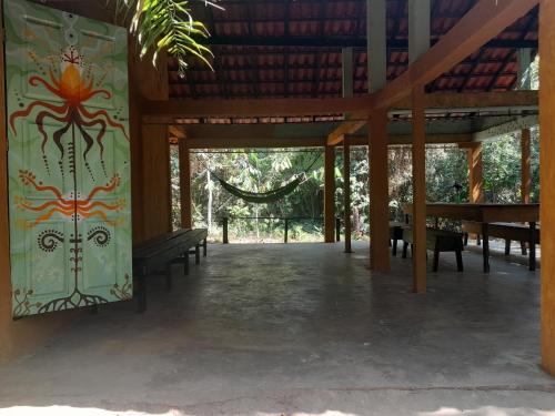 a pavilion with benches and a painting on the wall at Caminho das pedras-Medicina, Consciência e espiritualidade- Hospedaria na floresta com saída ao Igarapé in Alter do Chao