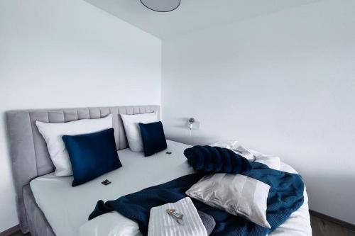 un lit blanc avec des oreillers bleus et blancs dessus dans l'établissement Apartment mit Wintergarten & Grüner Aussicht im Schwarzwald, à Löffingen