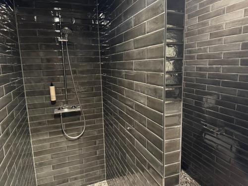 a bathroom with a shower with black tiles at Longstay Achterhoek in Zeddam