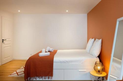 une chambre avec un lit blanc avec un mur orange dans l'établissement Le Loft Caché, à Carcassonne
