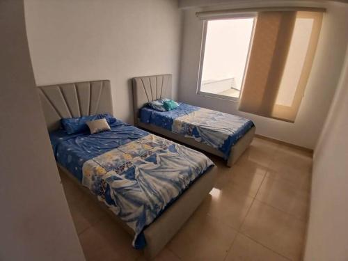 two beds in a room with a window at Espectacular Casa en Barbosa Santander in Barbosa