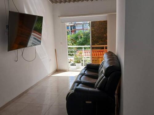 a living room with a black leather couch and a television at Espectacular Casa en Barbosa Santander in Barbosa