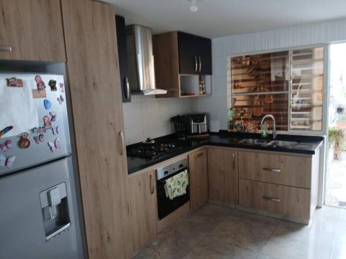 a kitchen with wooden cabinets and a white refrigerator at Espectacular Casa en Barbosa Santander in Barbosa