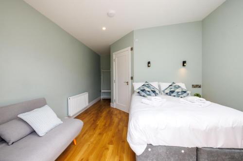 a bedroom with a white bed and a couch at Stoneyford Luxurious Cabins in Stonyford