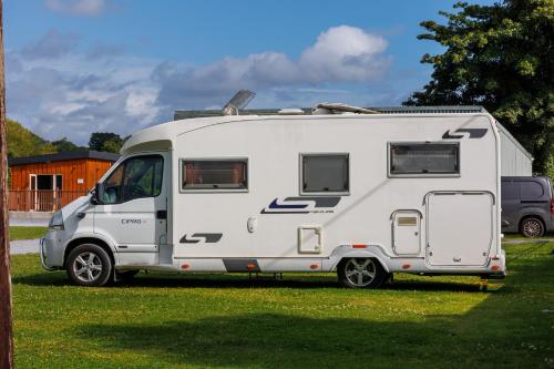 a white caravan parked in a grass field at Stoneyford Luxurious Cabins in Stonyford