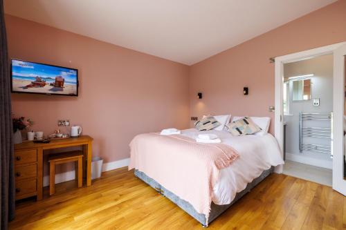 a bedroom with a bed and a tv on the wall at Stoneyford Luxurious Cabins in Stonyford