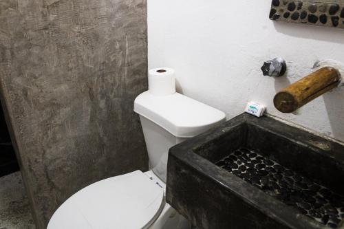 a bathroom with a white toilet and a sink at HiddenPort VHouse in Brisas de Zicatela