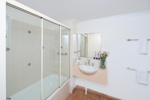 a bathroom with a glass shower and a sink at Park Regis Anchorage in Townsville
