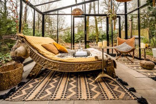 a glass house with a couch in the middle of a patio at Boutique Bungalow 2 met sauna, hottub en boskas in Rheezerveen