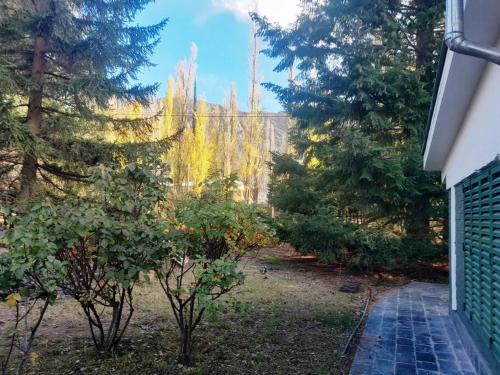 a garden with trees and a building in the background at Casa en medio de las montañas in Potrerillos