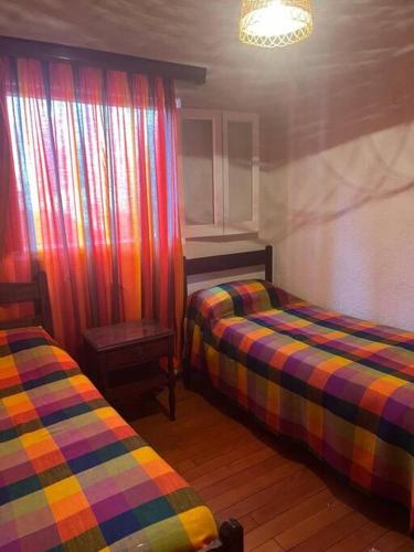 a room with two beds and a window with curtains at Casa en medio de las montañas in Potrerillos