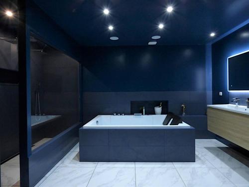 a blue bathroom with a tub and a tv at La Suite - Loft Spa in Tavernes