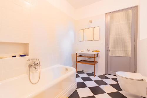 - une salle de bains blanche avec un sol en damier noir et blanc dans l'établissement Demeure Bajou - piscine privée - parc arboré, à Auterive