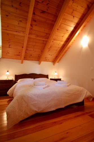 a bedroom with a large white bed with wooden ceilings at 7hills Waterfall Lodge by Ski Alure in Eptalofos