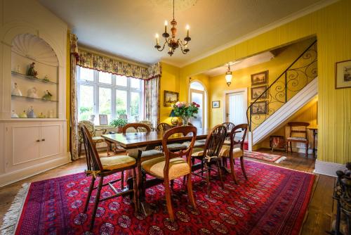 a dining room with a table and chairs on a red rug at Barnard House in Great Yarmouth