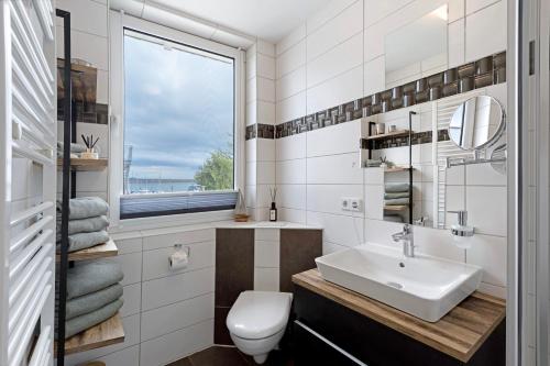 a bathroom with a sink and a toilet and a window at Fewo Seeschwalbe - Marina Mücheln in Mücheln