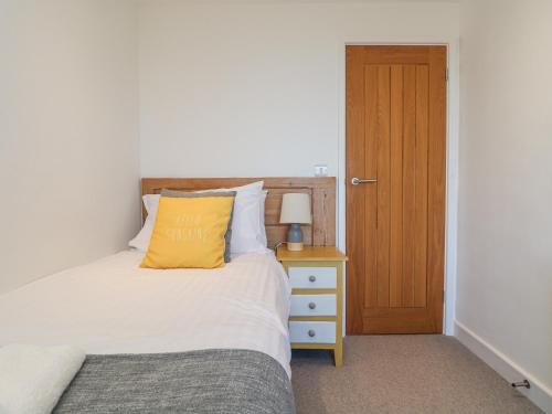a bedroom with a bed with a yellow pillow on it at Bal View in Lower Boscaswell