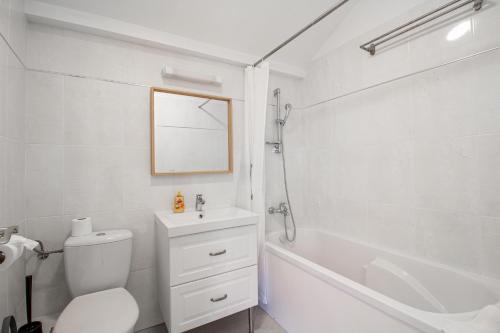 a white bathroom with a toilet and a bath tub at Sweet-mane in Roeser