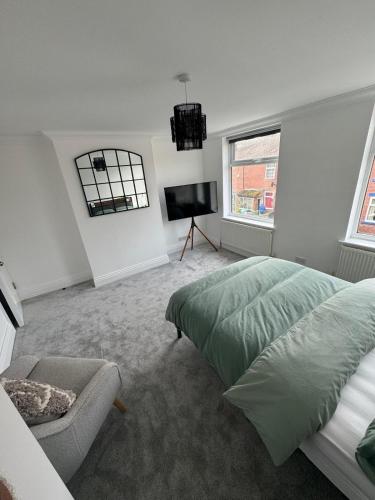 a bedroom with a bed and a chair and a television at The perfect room to rent in Altofts