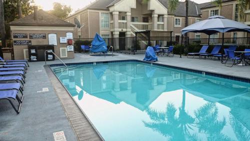 a swimming pool with chairs and an umbrella at Sonesta ES Suites Baton Rouge University at Southgate in Baton Rouge