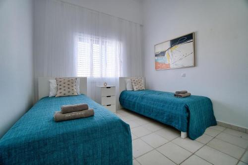 a bedroom with two beds with blue sheets and a window at Limnaria Gardens H 202 in Paphos City