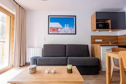 a living room with a couch and a table at Résidence Arya - Living Stone in Vars