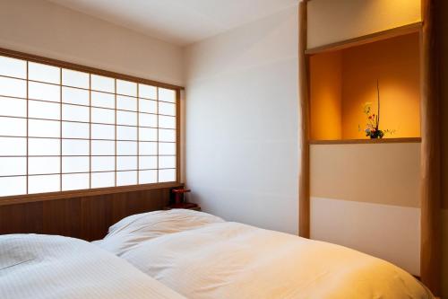 a bedroom with a bed and a window in it at Kappo Ryokan Yumesaki in Beppu