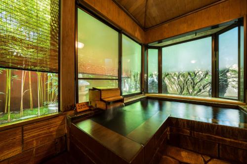 an empty room with a pool in front of windows at Kappo Ryokan Yumesaki in Beppu