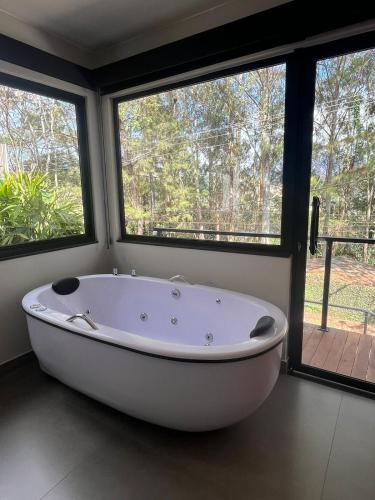 a large white bath tub in a room with windows at Villa Nogueira in Araras Petropolis