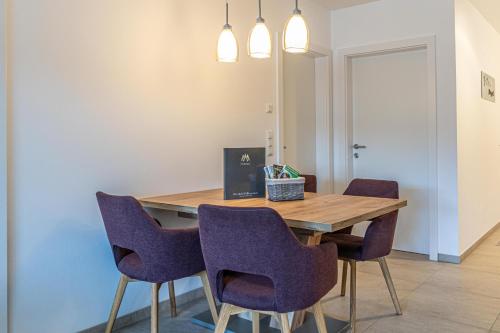 a dining room with a wooden table and purple chairs at Top 27 Alpe Maritima - Bergruh in Annenheim