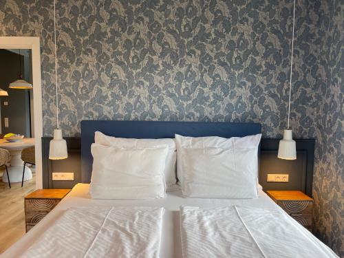 a bed with white pillows in a bedroom with a wallpaper at Alwine - Landhaus an den Spreewiesen in Rietz Neuendorf