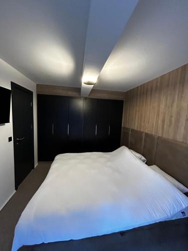 a bedroom with a large white bed with black cabinets at La Familia in Jahorina