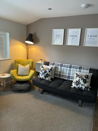 a living room with a couch and a yellow chair at The Hive Apartment in Marple
