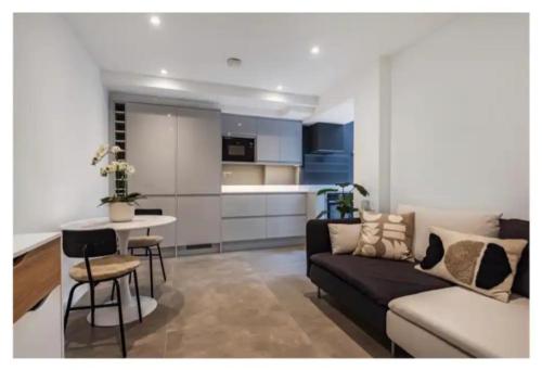 a living room with a couch and a table and a kitchen at Richmond Maisonette 3 bed, 2 bath & garden terrace in Richmond