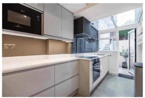 a kitchen with white cabinets and a stove top oven at Richmond Maisonette 3 bed, 2 bath & garden terrace in Richmond